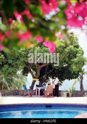 Ein Kellner nimmt eine Bestellung am Hauptpool im Steinfeld Estate Villa Resort in St. Lucia. Soufrière, St. Lucia. Stockfoto