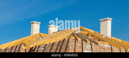 Dach-Konstruktion. Holzdach Rahmen, weiße Schornsteine und gelben Backstein-Hausbau Stockfoto