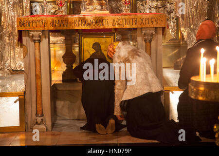 Jerusalem, Israel - 24. November 2013: Puigrims beten auf den Knien vor dem Altar Kreuzigungen in Heilig-Grab-Kirche in Jerusalem. Diese sto Stockfoto