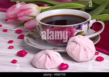 Valentinstag eleganten Stilleben mit Tulpen Blumen Tasse Kaffee Marshmallows Zephyr rotes Herzform zu unterzeichnen, auf weißem Hintergrund aus Holz Stockfoto