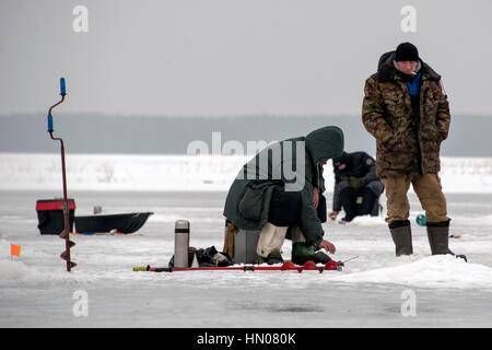 Ein russischer Mann auf kalten Wintertag wie er sitzt auf Eis Angeln an einem Fluß im Moskauer Gebiet. Eisfischen ist ein beliebtes Hobby in Russland Stockfoto