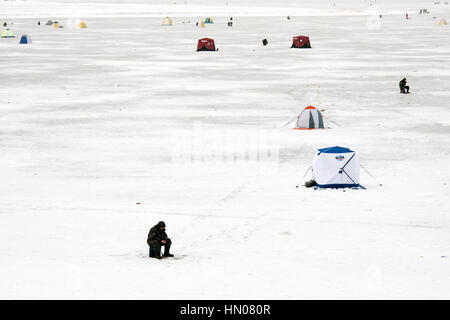 Ein russischer Mann auf kalten Wintertag wie er sitzt auf Eis Angeln an einem Fluß im Moskauer Gebiet. Eisfischen ist ein beliebtes Hobby in Russland Stockfoto