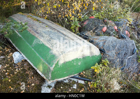 Alte grüne Ruderboot liegt in der Nähe von Fischernetzen an der Küste Stockfoto