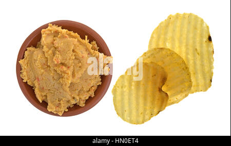 Draufsicht auf eine kleine Schüssel mit Hummus-Artischocken-Dip mit Kartoffel-Chips auf der Seite isoliert auf einem weißen Hintergrund. Stockfoto