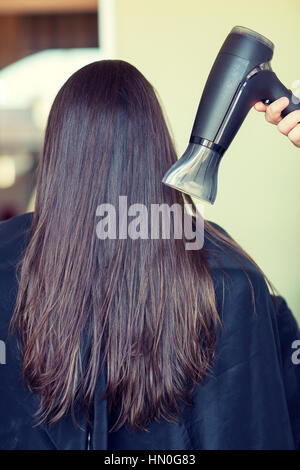 Stylist Hand mit Ventilator trocknet Frau Haare im salon Stockfoto