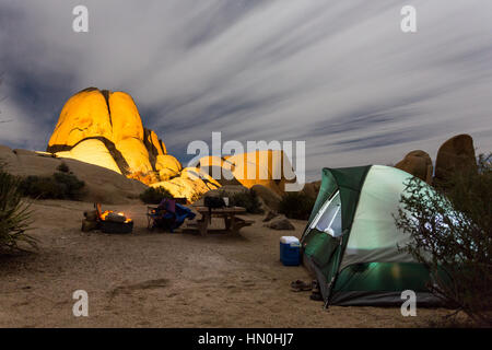 Ein Zelt sitzt ein Lagerfeuer in der Nacht auf einem Campingplatz in Joshua Tree National Park. Stockfoto