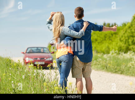 paar Trampen und Anhalten von Autos auf Land Stockfoto