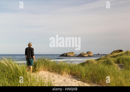 Ein Mann schaut auf Meer-Stacks von den Sanddünen von Cannon Beach, Oregon. Stockfoto