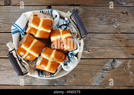 Ostern Hot Cross Buns in einem Korb, nach unten gerichtete Blick auf einem rustikalen Holz Hintergrund Stockfoto