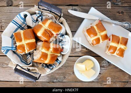 Ostern Hot Cross Brötchen, Überkopf-Szene mit Korb und Tablett auf rustikalen Holz Hintergrund Stockfoto