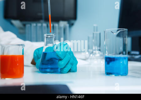 Laboratorian mit Kolben auf Tisch im Chemie-Labor Stockfoto