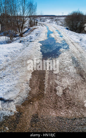 Die Straße im Frühjahr Auftauen mit Schlamm und Pfützen Stockfoto