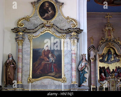Die Église Notre-Dame de la Visitation in Mothern, Elsass, Bas-Rhin, mit einem Nebenaltar mit Statuen der Heiligen Teresa von Avila und der Heiligen Elisabeth sowie zwei Gemälden: „Education de la Vierge“ und „St-Joseph et l'enfant Jésus“, beide aus dem 19. Jahrhundert. Stockfoto