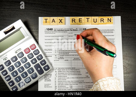 Business-Frau füllt das Steuerformular 1040 mit Stift und Taschenrechner Stockfoto