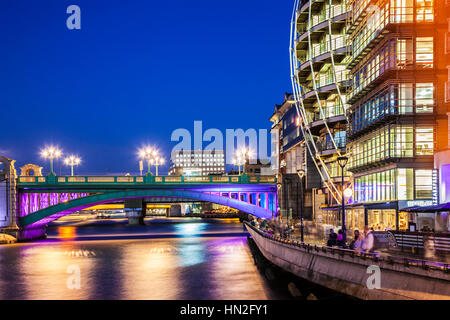 Teil der Southwark Bridge und Bankside entlang der Themse in London in der Nacht. Stockfoto