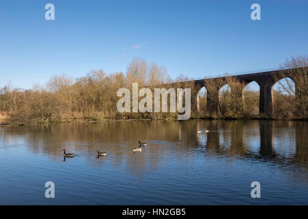 Eisenbahnviadukt spiegelt sich im See im rötlich Vale Country Park, Manchester, England Stockfoto