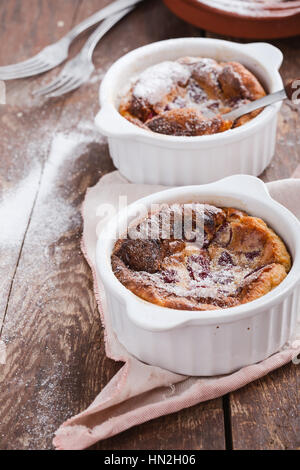 Hausgemachte traditionelle französische Dessert Kirsch Clafoutis in Keramik Förmchen auf rustikalen Tisch Stockfoto