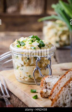 Ei-Sprung-Sandwich mit Grün von Frühlingszwiebeln für gesunden und leckeren Brunch am rustikalen hölzernen Schneidebrett Stockfoto