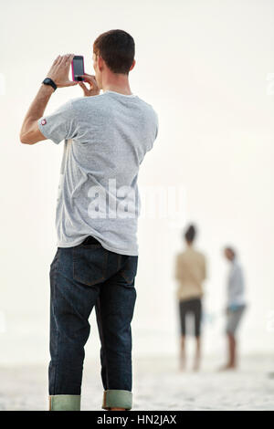 Junger Mann mit dem Fotografieren am Strand. Stockfoto