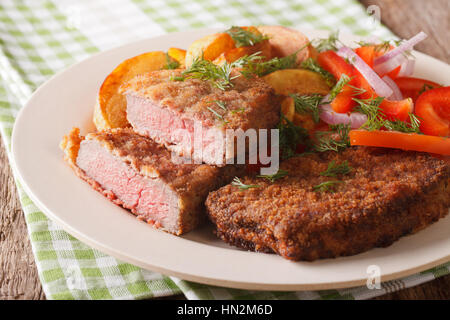 Gebratenes Rumpsteak in Paniermehl und frisches Gemüse, Ofenkartoffel hautnah auf dem Tisch. Horizontale Stockfoto