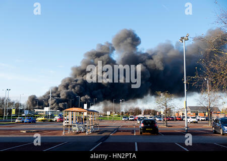 Großes Fabrikfeuer mit dicken schwarzen Rauchwolken Stockfoto