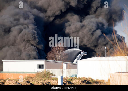 Großes Fabrikfeuer mit dicken schwarzen Rauchwolken Stockfoto