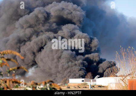 Großes Fabrikfeuer mit dicken schwarzen Rauchwolken Stockfoto