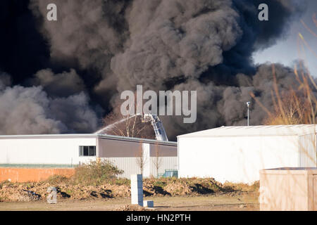 Großes Fabrikfeuer mit dicken schwarzen Rauchwolken Stockfoto