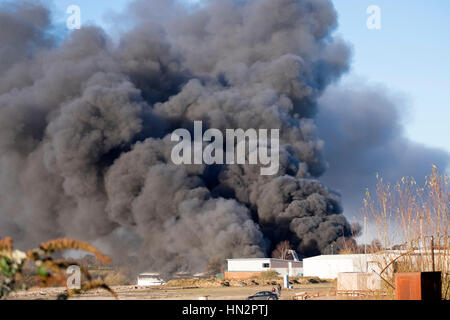 Großes Fabrikfeuer mit dicken schwarzen Rauchwolken Stockfoto