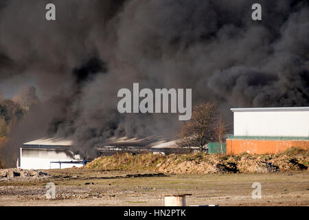 Großes Fabrikfeuer mit dicken schwarzen Rauchwolken Stockfoto