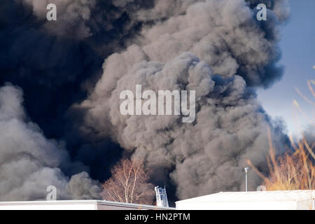 Großes Fabrikfeuer mit dicken schwarzen Rauchwolken Stockfoto