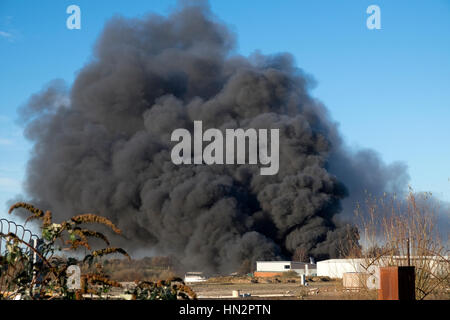 Großes Fabrikfeuer mit dicken schwarzen Rauchwolken Stockfoto