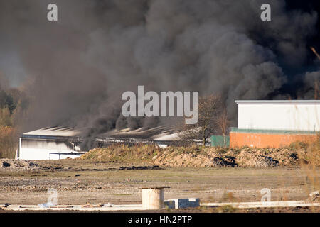 Großes Fabrikfeuer mit dicken schwarzen Rauchwolken Stockfoto