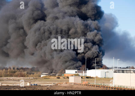 Großes Fabrikfeuer mit dicken schwarzen Rauchwolken Stockfoto