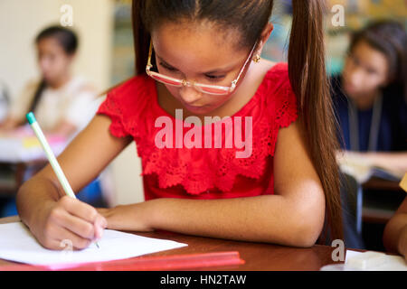 Jugend und Bildung. Gruppe von hispanic Studenten in der Klasse in der Schule während der Lektion. Mädchen mit Papier für Aufnahme-Test, Prüfung Stockfoto