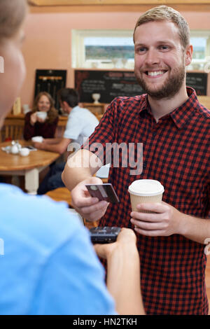 Kunden zahlen für Kaffee zum Mitnehmen mit kontaktlosen Terminal Stockfoto