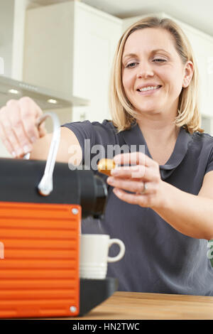 Frau mit Kapsel Kaffeemaschine In der Küche Stockfoto