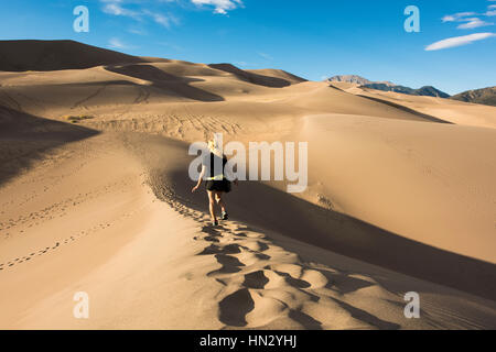 Junge blonde Frau zu Fuß auf den Great Sand Dunes in Colorado Stockfoto