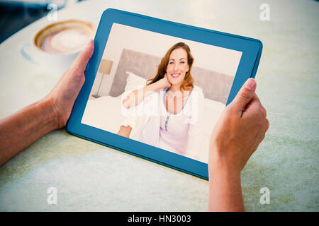 Lächelnde Frau auf Bett gegen die Person, die Tablet-Computer am Tisch im Café sitzen Stockfoto