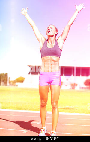 Aufgeregt Sportlerin posiert nach Sieg auf der Rennstrecke Stockfoto