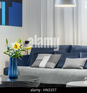 Gelbe Blumen in Vase auf moderner Couchtisch in stilvollen blau und grau-Wohnzimmer Stockfoto