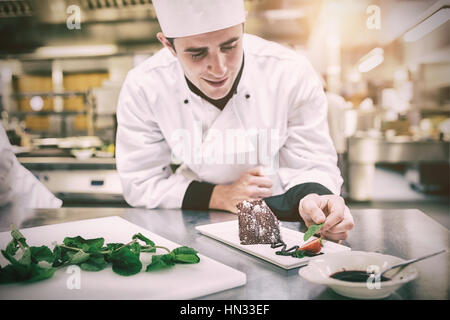 Lächelnd Chef setzen Minze mit seinem Dessert in der Küche Stockfoto