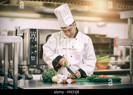 Happy Chef schneiden Tomaten in Profi-Küche Stockfoto