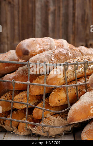 Verschiedene Arten von Baguettes im Metallkorb in Bäckerei auf hölzernen Hintergrund und leeren Raum für text Stockfoto