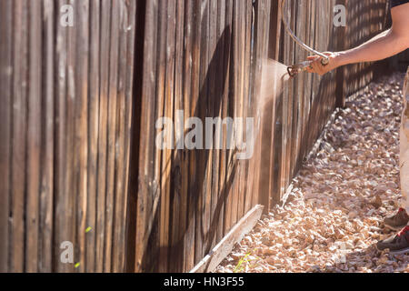 Professionelle Maler Haus Garten Zaun mit Beize sprühen. Stockfoto
