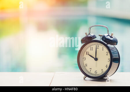 10:00 Retro-Uhr um den Swimmingpool im freien Zeit Ferienkonzept. Stockfoto