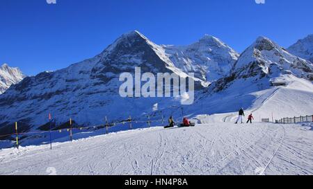 Ski-Piste und Schnee bedeckte Berge Eiger, Monch und Lauberhorn. Wintertag in Grindelwald, Schweizer Alpen. Stockfoto