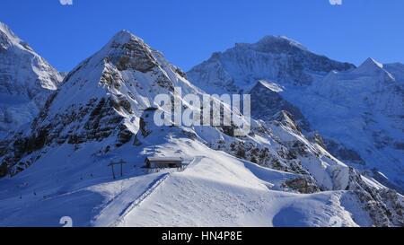 Winter-Szene in Grindelwald, Schweizer Alpen. Schneebedeckte Berge, Lauberhorn und Jungfrau, Bergstation der Seilbahn. Stockfoto