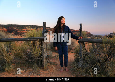 Eine hübsches Tween Mädchen steht mit einem rustikalen Zaun in eine Wüstenlandschaft im Coral Pink Sand Dunes State Park in Utah. Stockfoto