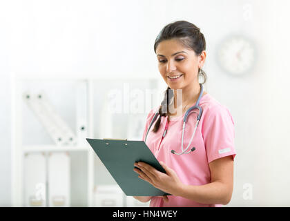 Schönes Lächeln Ärztin halten Patienten Verlaufsliste in Zwischenablage Pad im Krankenzimmer. Gesunder Lebensstil-Konzept Stockfoto